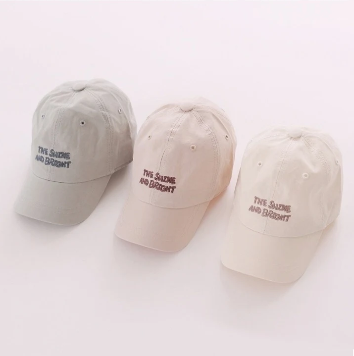 Three baseball caps in gray, beige, and white with text on a white background