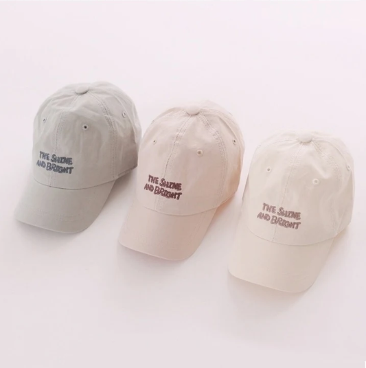 Three baseball caps in gray, beige, and white with text on a white background